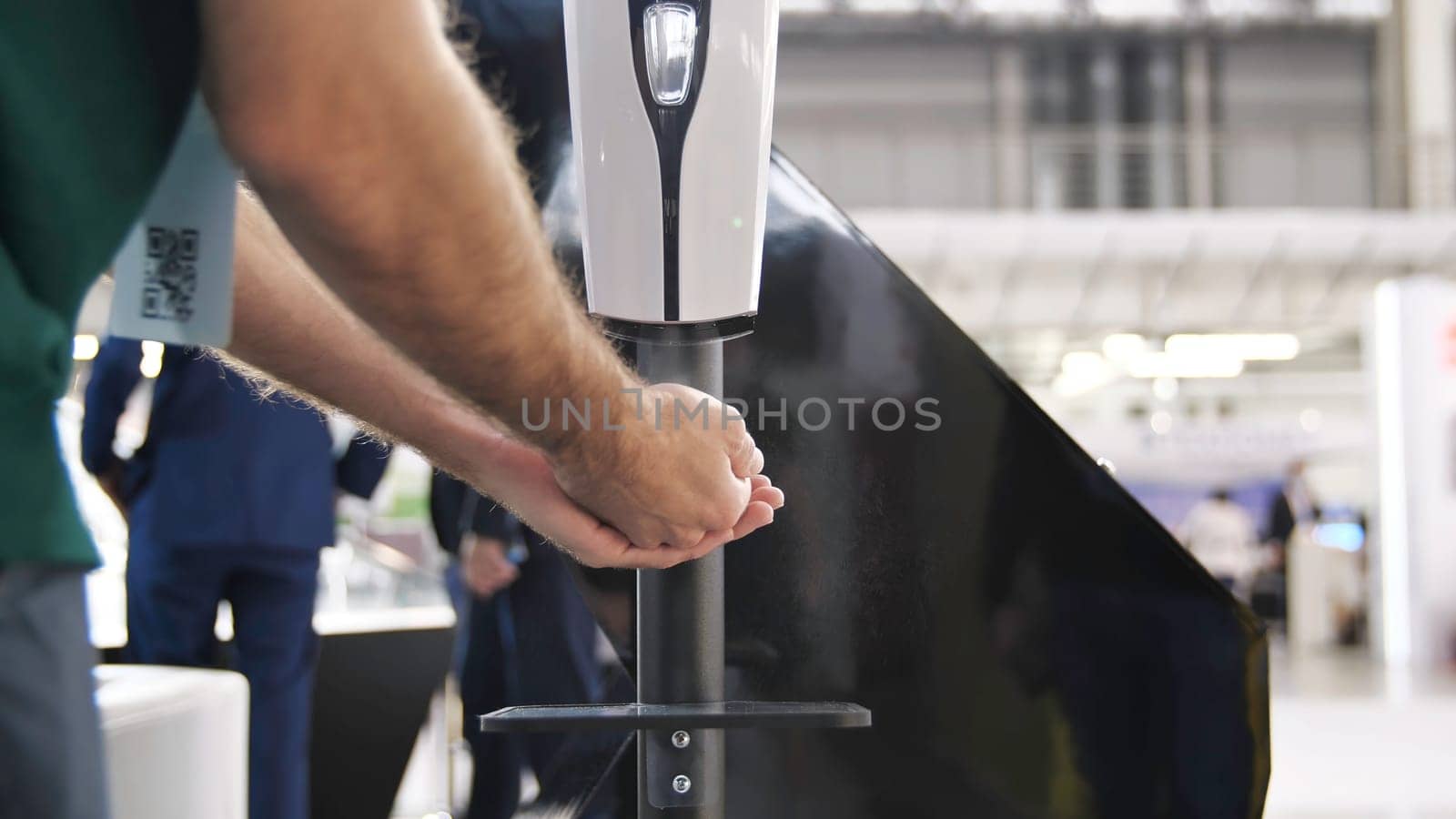 Hygiene and healthcare, coronavirus epidemic preventive measures concept. Hand using automatic touchless sanitizing dispenser with antiseptic during second wave of COVID-19 Pandemic.