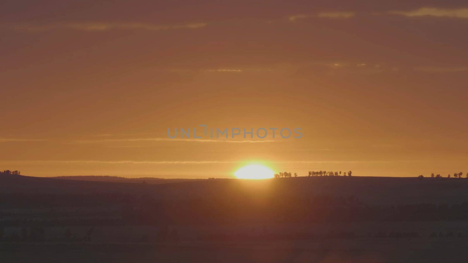 Natural Sunrise Over Field Or Meadow. Bright Dramatic Sky And Dark Ground. Countryside Landscape Under Scenic Colorful Sky At Sunset Dawn Sunrise. Sun Over Skyline, Horizon. Warm Colours.