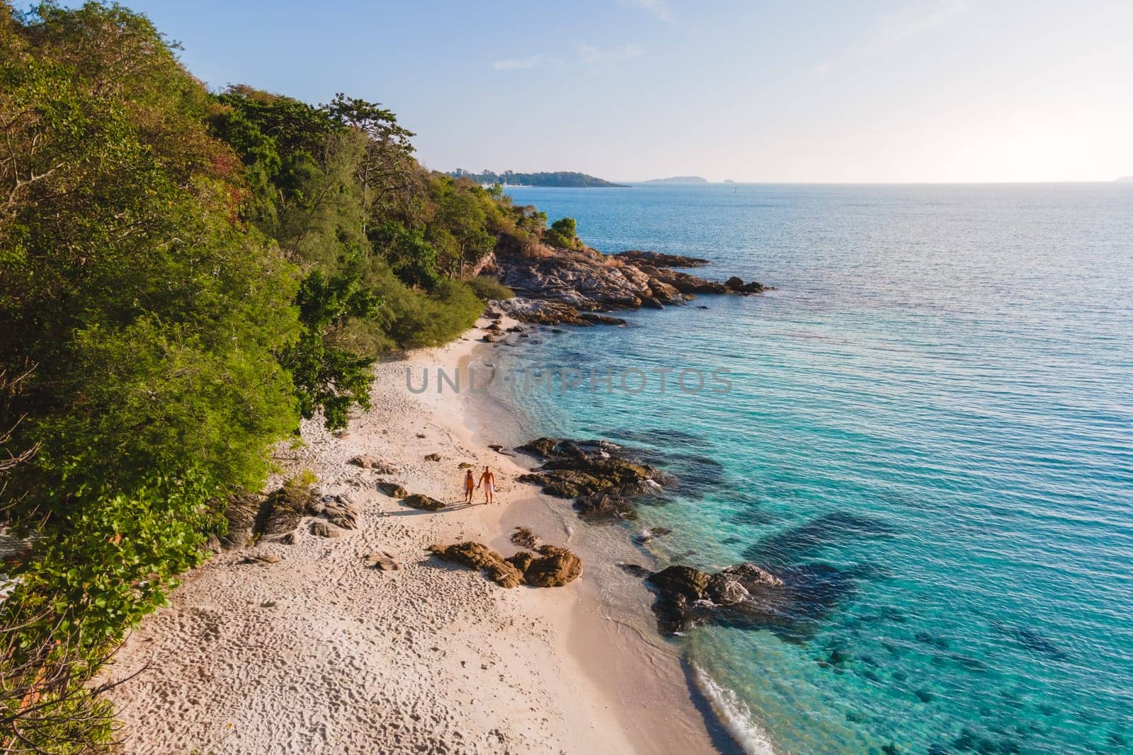 Koh Samet Island Thailand, aerial drone view from above at a couple of men and woman on the beach of Samed Island in Thailand with a turqouse colored ocean and a white tropical beach during holidays