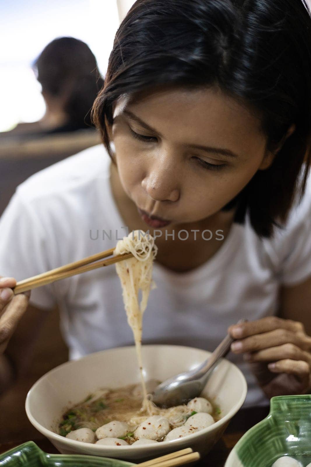 Close up of Woman eating noodle in white bowl.
