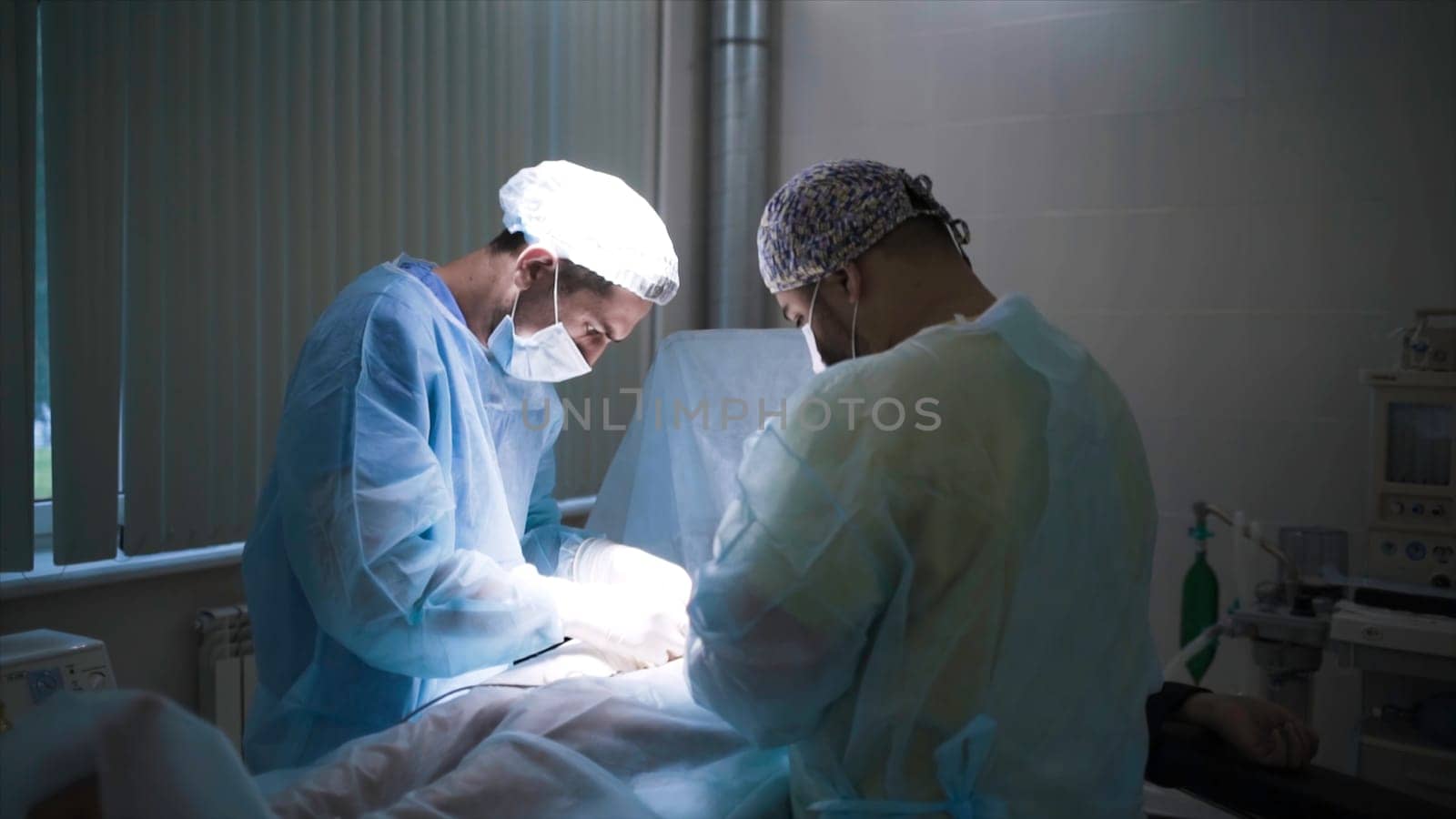 Close-up of professional surgeons performing surgery on person. Action. Two specialized surgeons carefully perform operation under anesthesia.