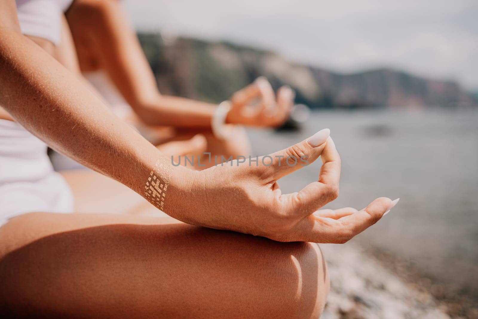 Woman sea yoga. Happy women meditating in yoga pose on the beach, ocean and rock mountains. Motivation and inspirational fit and exercising. Healthy lifestyle outdoors in nature, fitness concept. by panophotograph