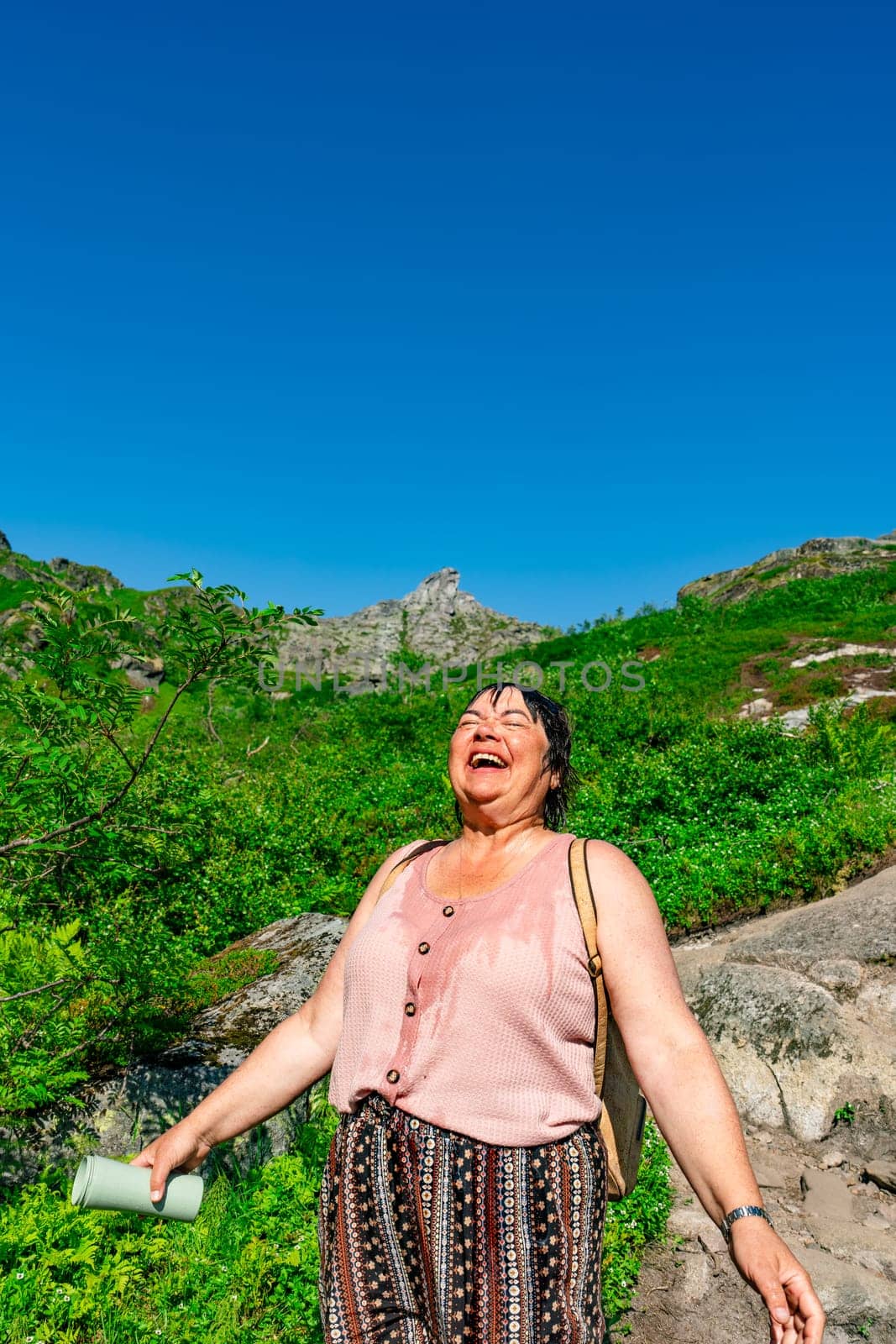 A tourist embraces a mountain escape by cooling down with cold water on a hot sunny day. The scenic beauty of the mountains creates a sense of tranquility and relaxation.
