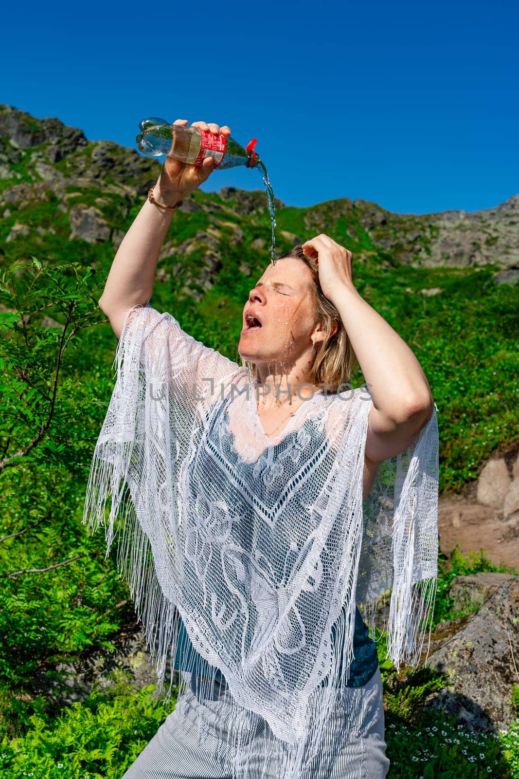 Amidst the mountain oasis, a tourist enjoys a refreshing moment with cold water on a hot sunny day. The tranquil atmosphere and stunning natural beauty create an idyllic setting for relaxation.