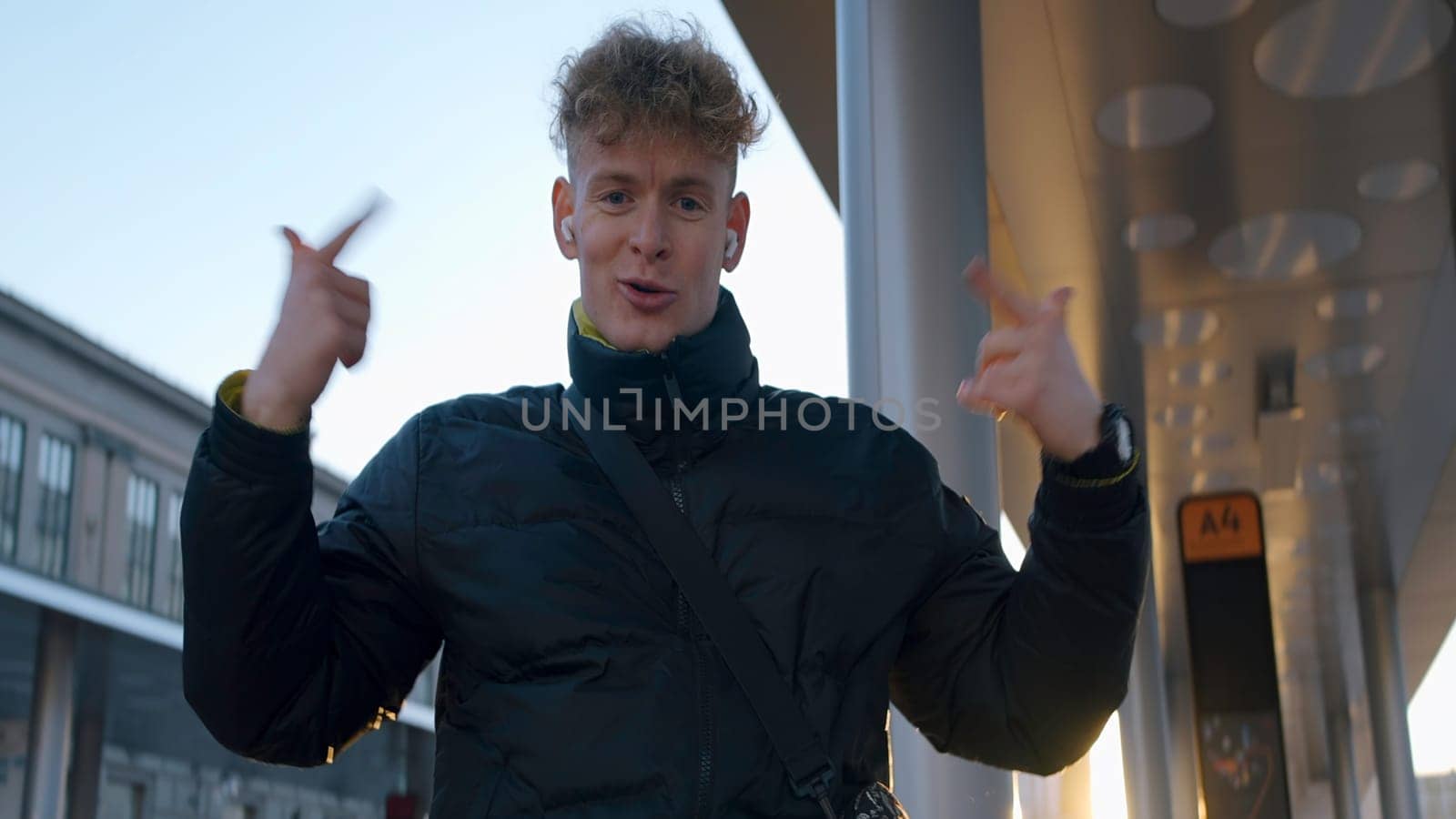 Young man dancing in modern style on street. Action. Man is dancing modern cool dance. Young man in jacket dancing on sunny day on street.
