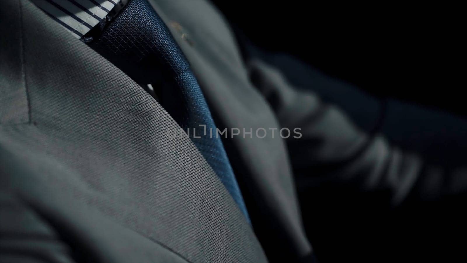 Close up of businessman in formal suit driving a car. Handsome young man sitting at wheel of car. Guy spending time in traffic jam and looking at car's interior.