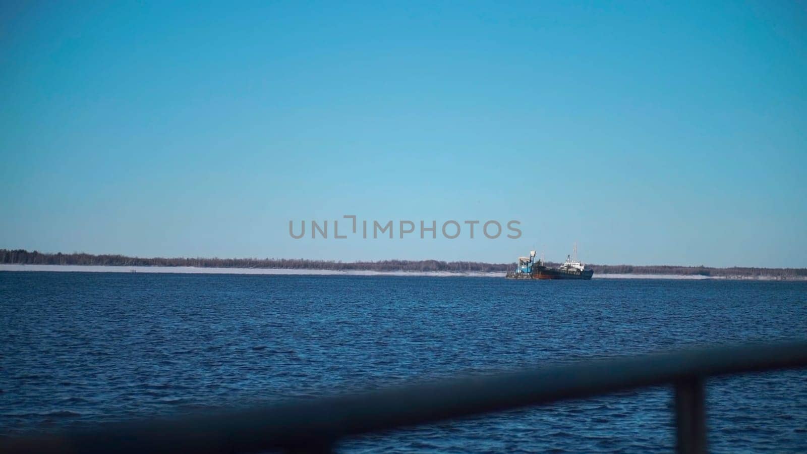 A snowy sea with ships.Clip. Huge ships with cargo move through the snowy sea, behind which the forest is visible. High quality FullHD footage