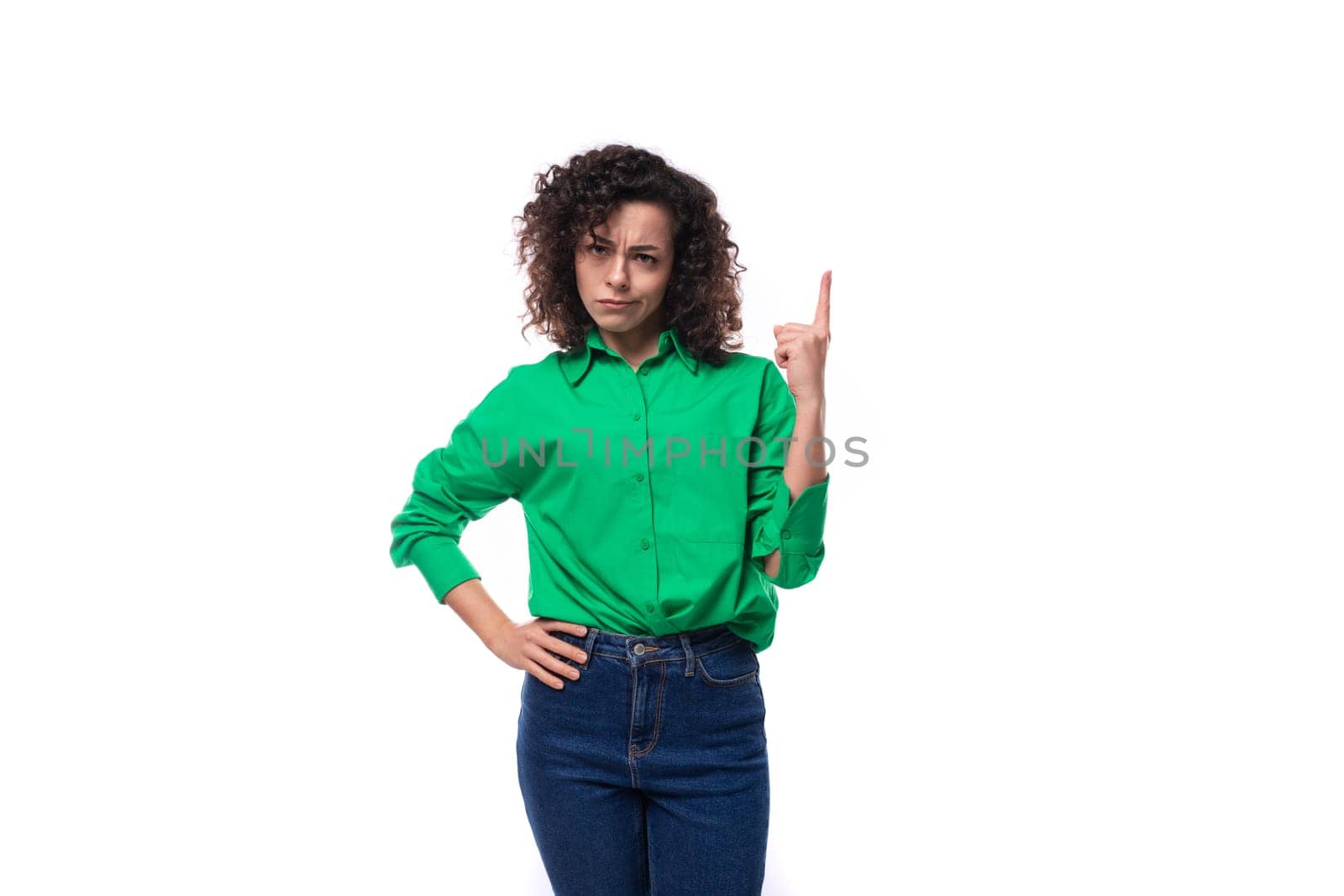 young caucasian lady with black curls dressed in a green shirt is actively gesturing on a white background with copy space by TRMK