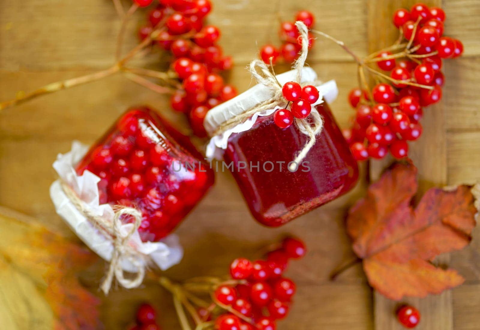 viburnum jam. Red juicy berries of a viburnum with sugar in a glass jar on a dark wooden background. For making jam, tea.