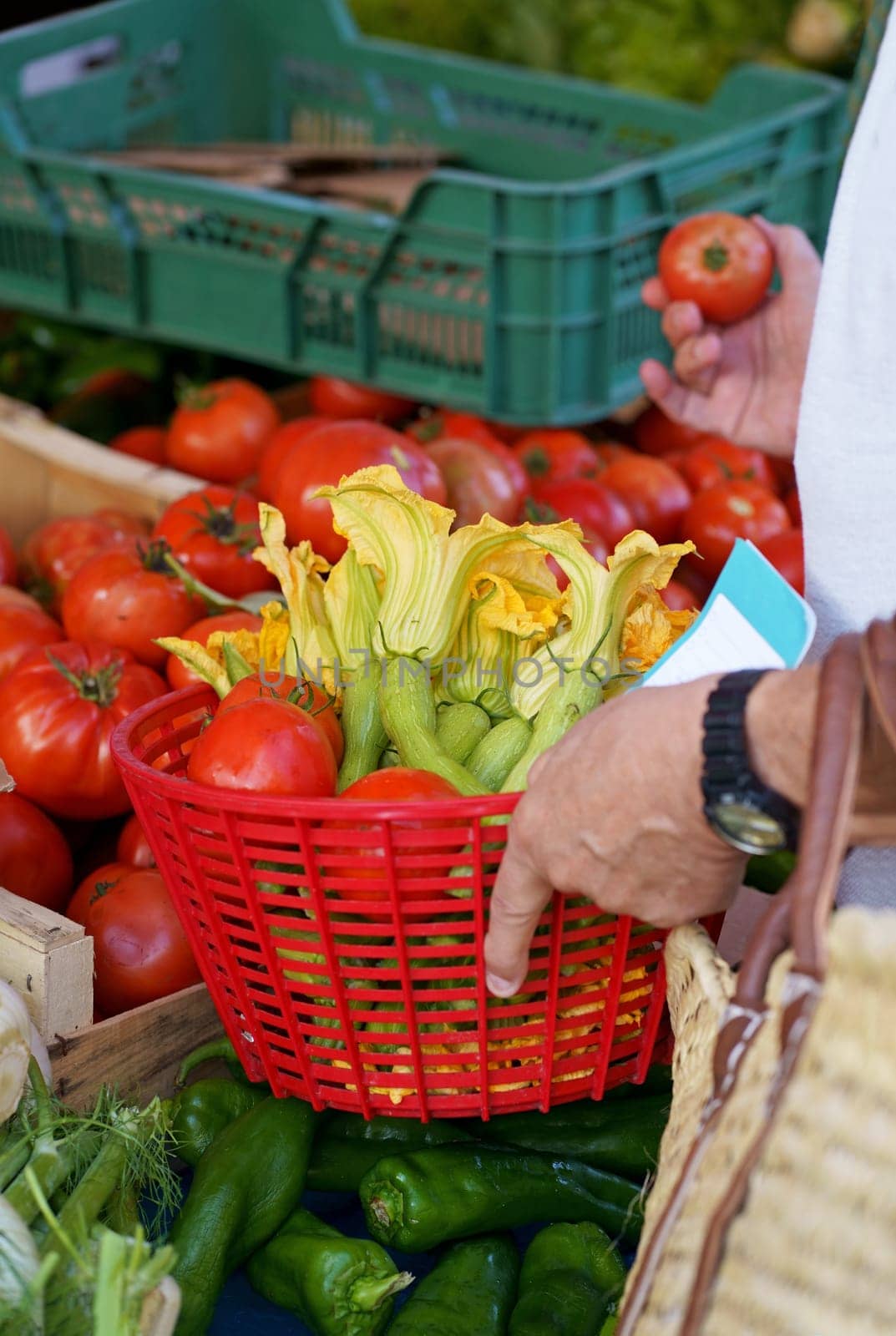 A man buys vegetables at a French market. Close-up of a man shopping, collecting fresh tomatoes and zucchini in a grocery cart at a local market, store or supermarket. by aprilphoto