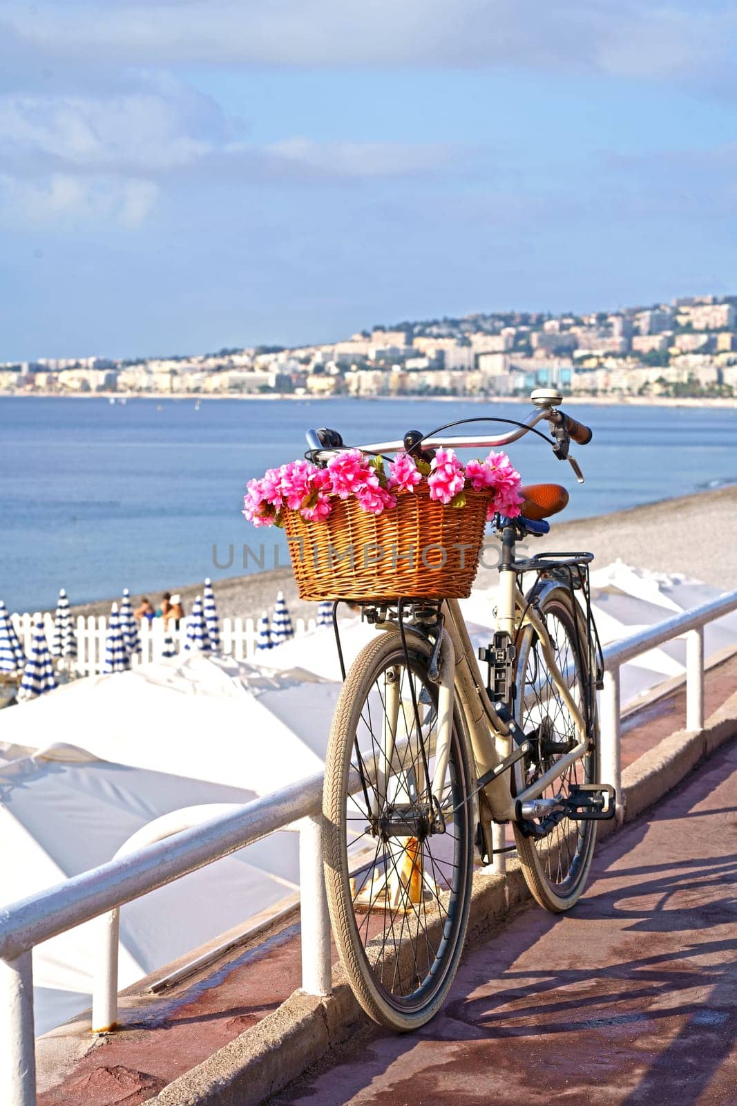 France. Nice. Bicycle with a beautiful basket filled with pink flowers in front of the sea by aprilphoto