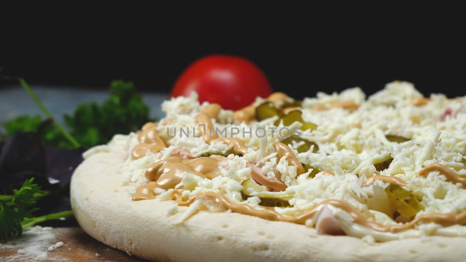 Close-up of chef preparing Italian pizza. Frame. Professional chef with gloves lay cucumber slices on pizza. Cooking Italian pizza on black isolated background.