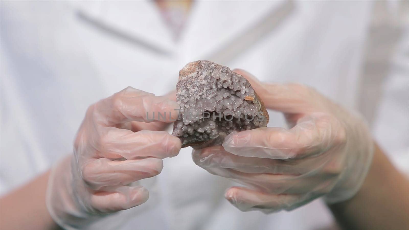 Bright grey ruby crystal ore in hands with gloves. Crystallization is the natural or artificial process by which a solid forms in laboratory