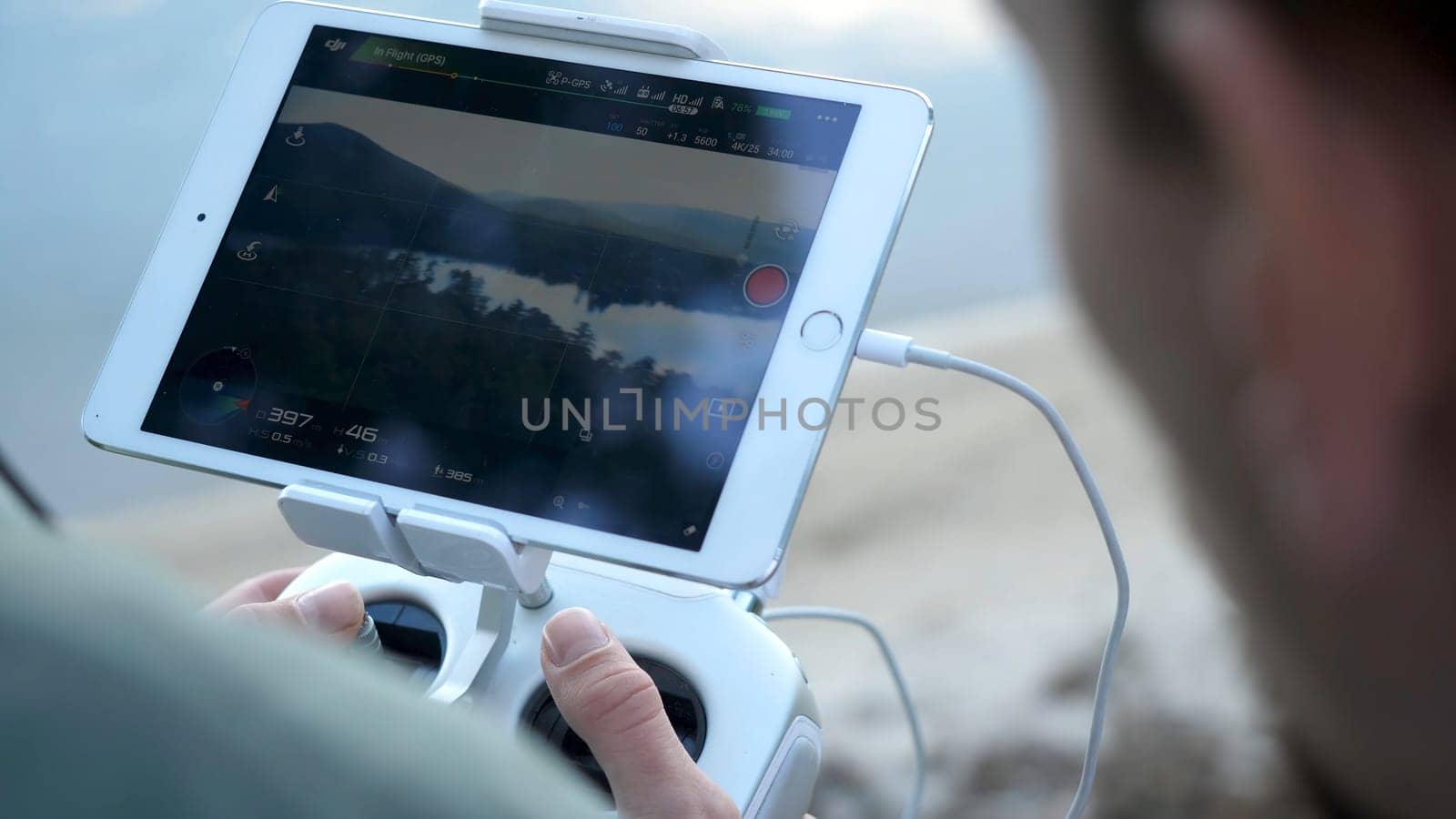 Close-up of man's hands with a remote control flying a small quadcopter toy at nature.
