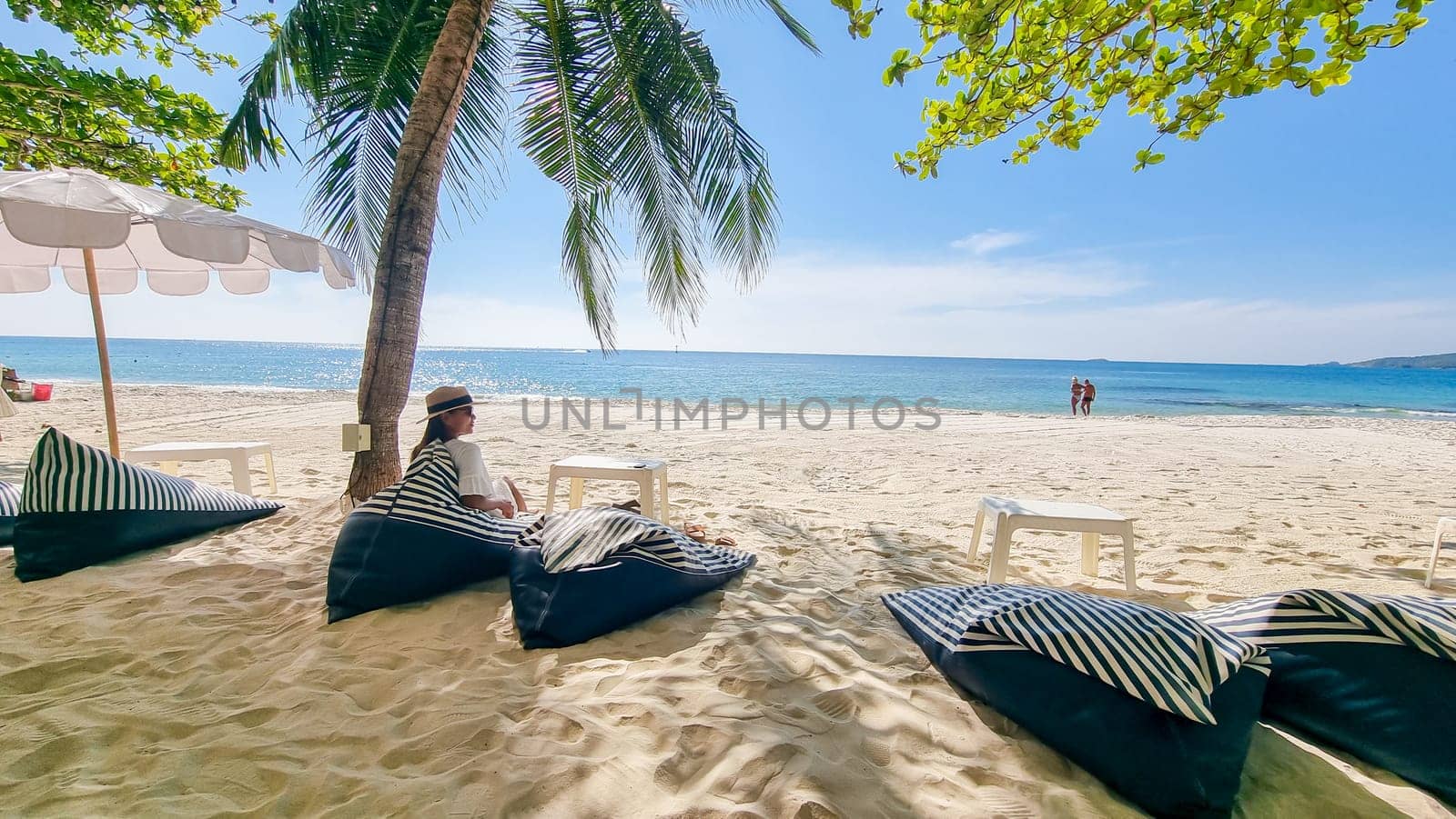 Asian woman on a beach chair on the beach of Koh Samet Island Rayong Thailand, the white tropical beach of Samed Island with a turqouse colored ocean on a sunny day