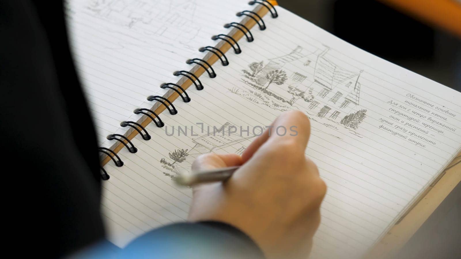Hands holding pencil to write or to draw in a notebook. Adult colouring with soft tip pencils. Female hand drawing pencil in the notebook close-up p