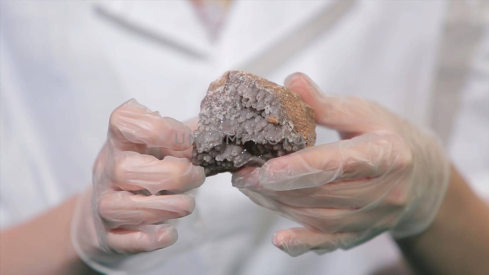 Bright grey ruby crystal ore in hands with gloves. Crystallization is the natural or artificial process by which a solid forms in laboratory