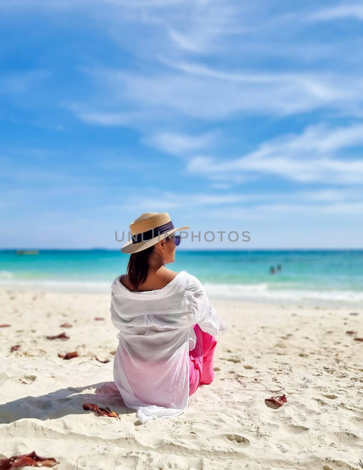 Asian woman sitting on the beach of Koh Samet Island Rayong Thailand, the white tropical beach of Samed Island with a turqouse colored ocean