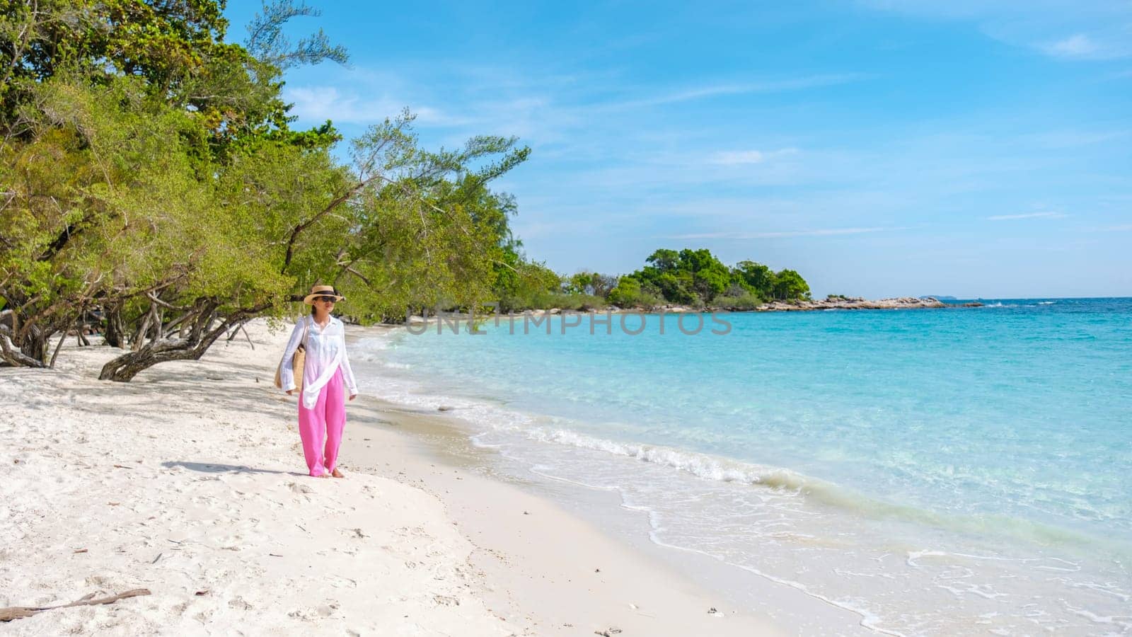 Asian Thai woman walking on the beach of Koh Samet Island Rayong Thailand, the white tropical beach of Samed Island with a turqouse colored ocean