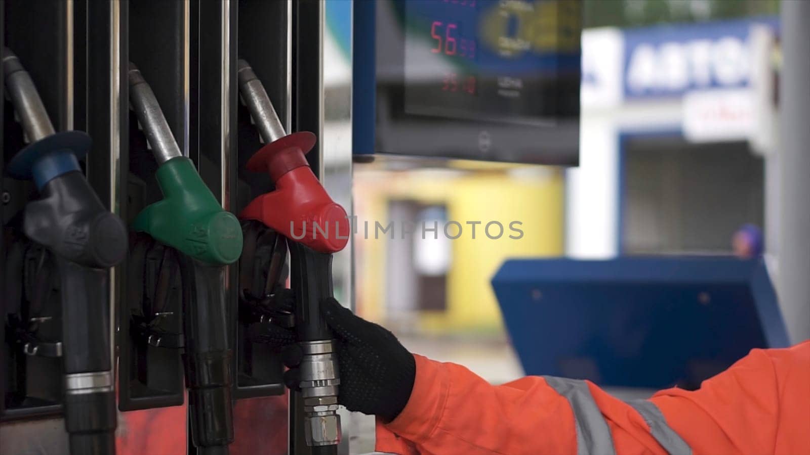 Oil, fuel nozzles hang on the machine in the petrol station. Clip. Close-up of a men's hand using a fuel nozzle at a gas station. Petrol station. Filling station. Petrol. Gasoline. Man holding a gasoline nozzle. Petrol pump.