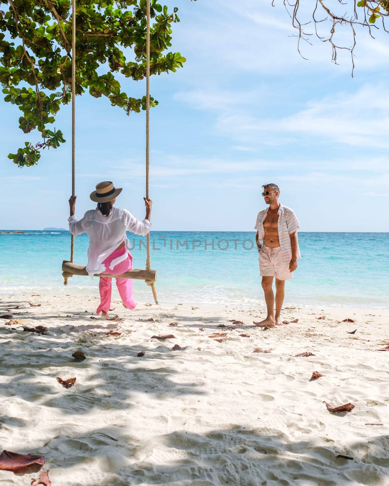 A couple of men and woman at a swing on the beach of Koh Samet Island Rayong Thailand by fokkebok