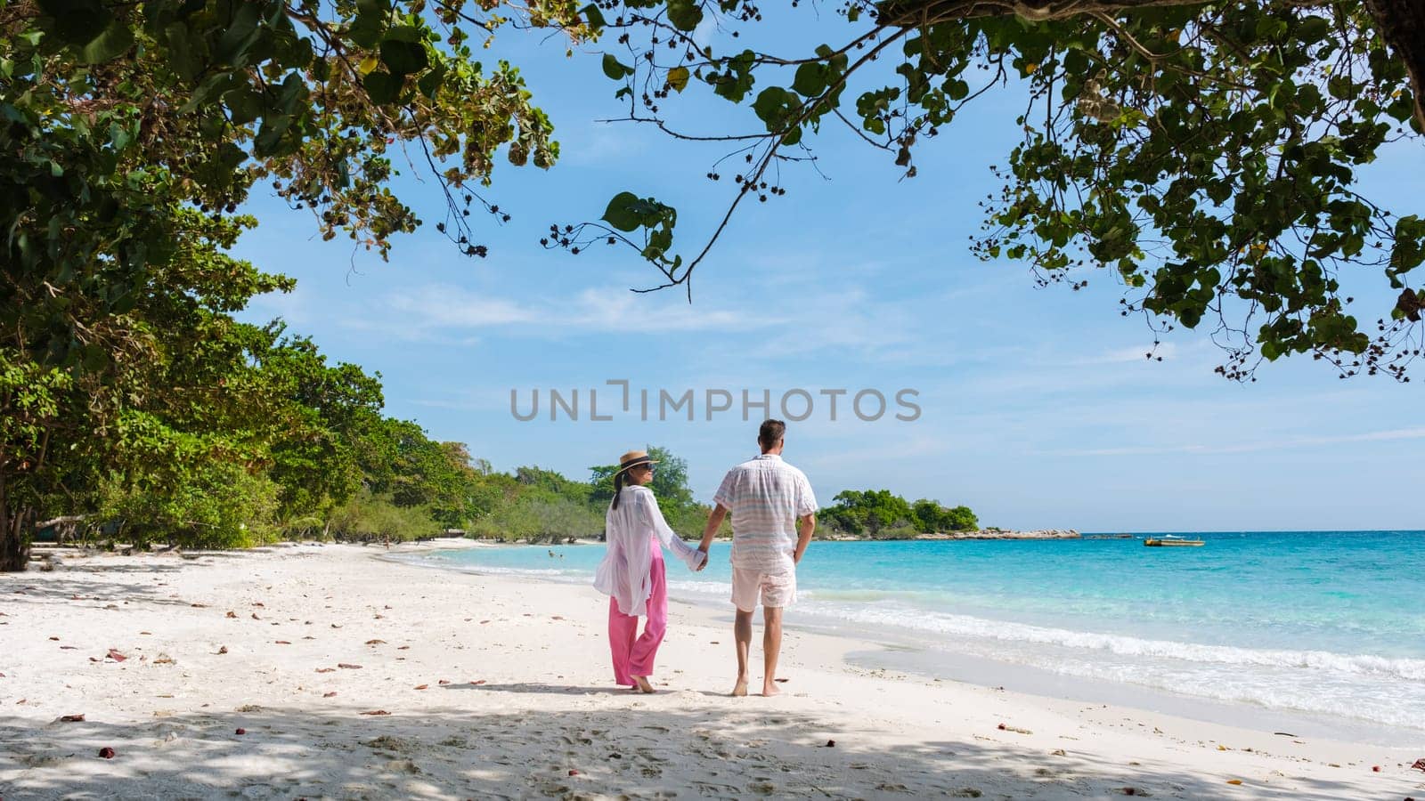 A couple of men and woman walking on the beach of Koh Samet Island Rayong Thailand