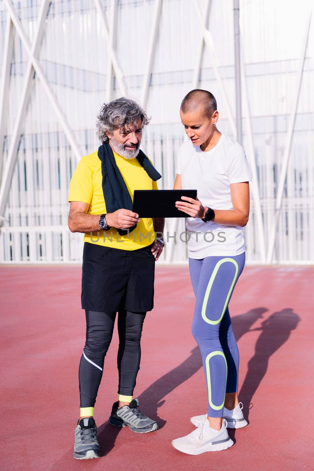 senior man planning workout with personal trainer by raulmelldo