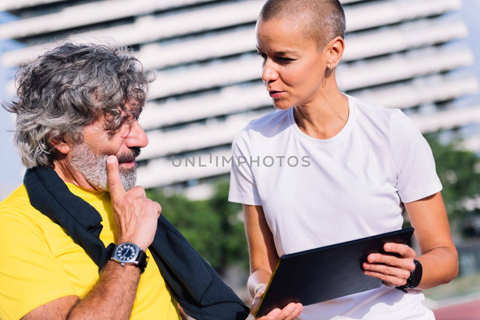 female personal trainer planning workout with a tablet for a senior sports man, concept of healthy and active lifestyle in middle age