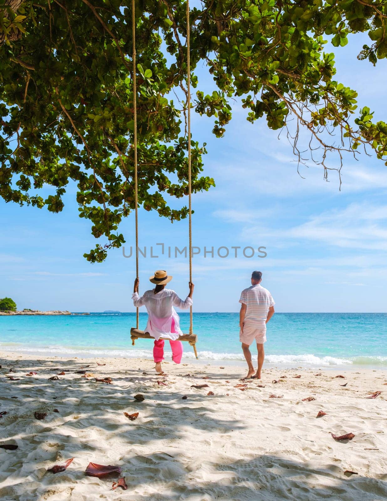 A couple of men and woman at a swing on the beach of Koh Samet Island Rayong Thailand by fokkebok