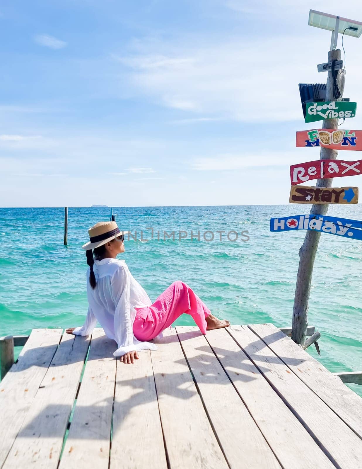 Asian woman at a wooden pier in the ocean of Koh Samet Island Rayong Thailand, the white tropical beach of Samed Island with a turqouse colored ocean