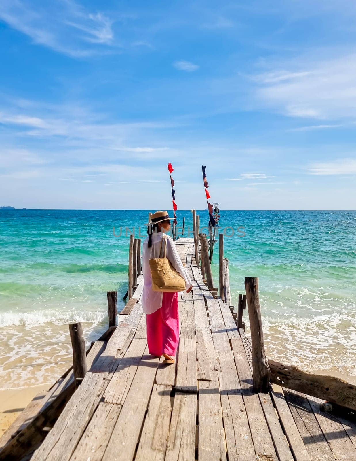 Asian woman at a wooden pier in the ocean of Koh Samet Island Rayong Thailand, the white tropical beach of Samed Island with a turqouse colored ocean