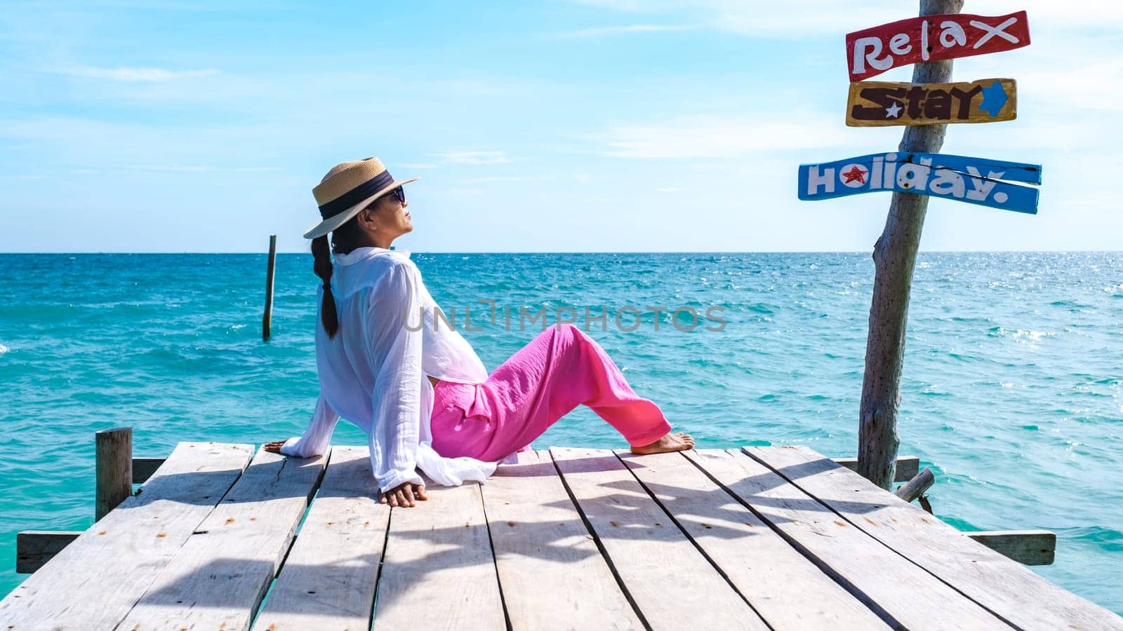 Asian woman at a wooden pier in the ocean of Koh Samet Island Rayong Thailand, the white tropical beach of Samed Island with a turqouse colored ocean