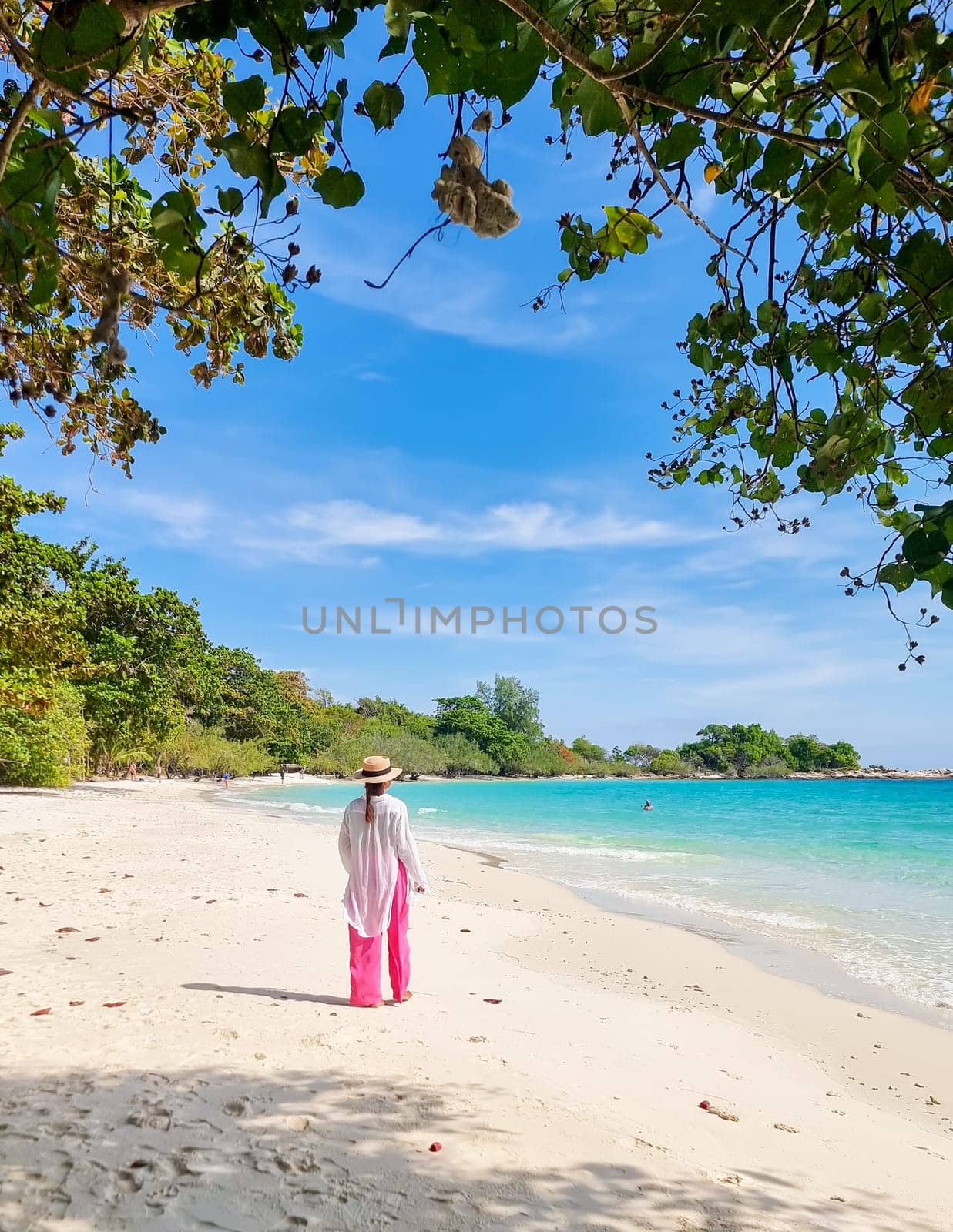Asian woman relaxing at the beach of Koh Samet Island Rayong Thailand, the white tropical beach of Samed Island with a turqouse colored ocean