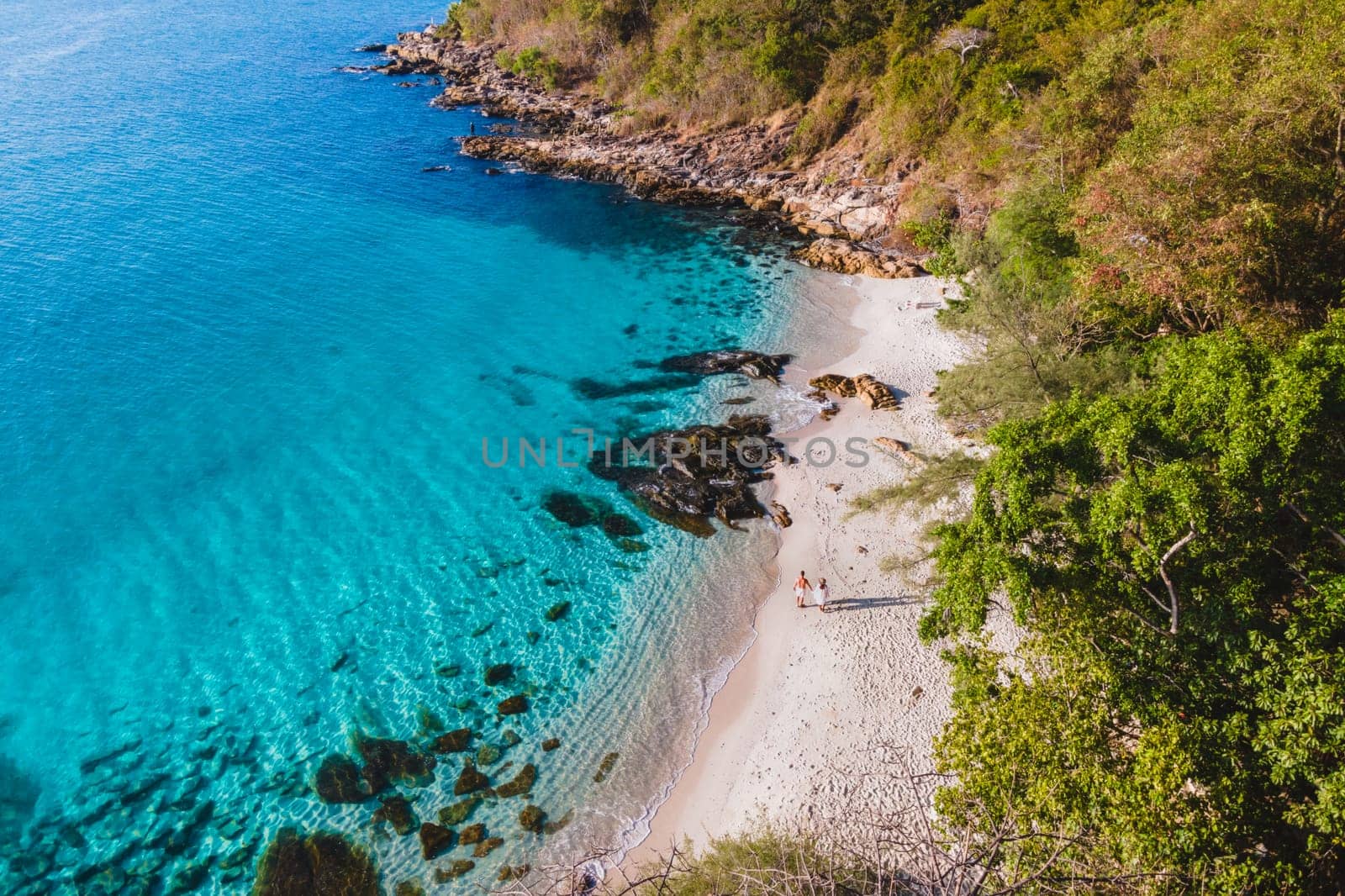 a couple of men and woman on the beach of Samed Island in Thailand with a turqouse colored ocean and a white tropical beach. Koh Samet Thailand