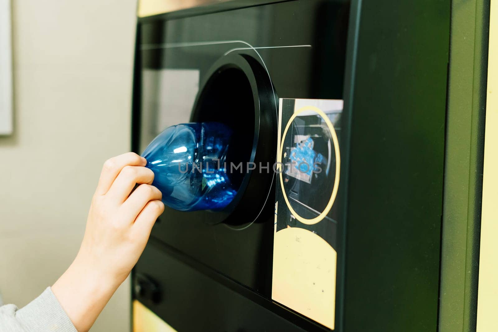 Reverse vending recycling machine that dispenses cash. Man hand puts plastic bottle to machine