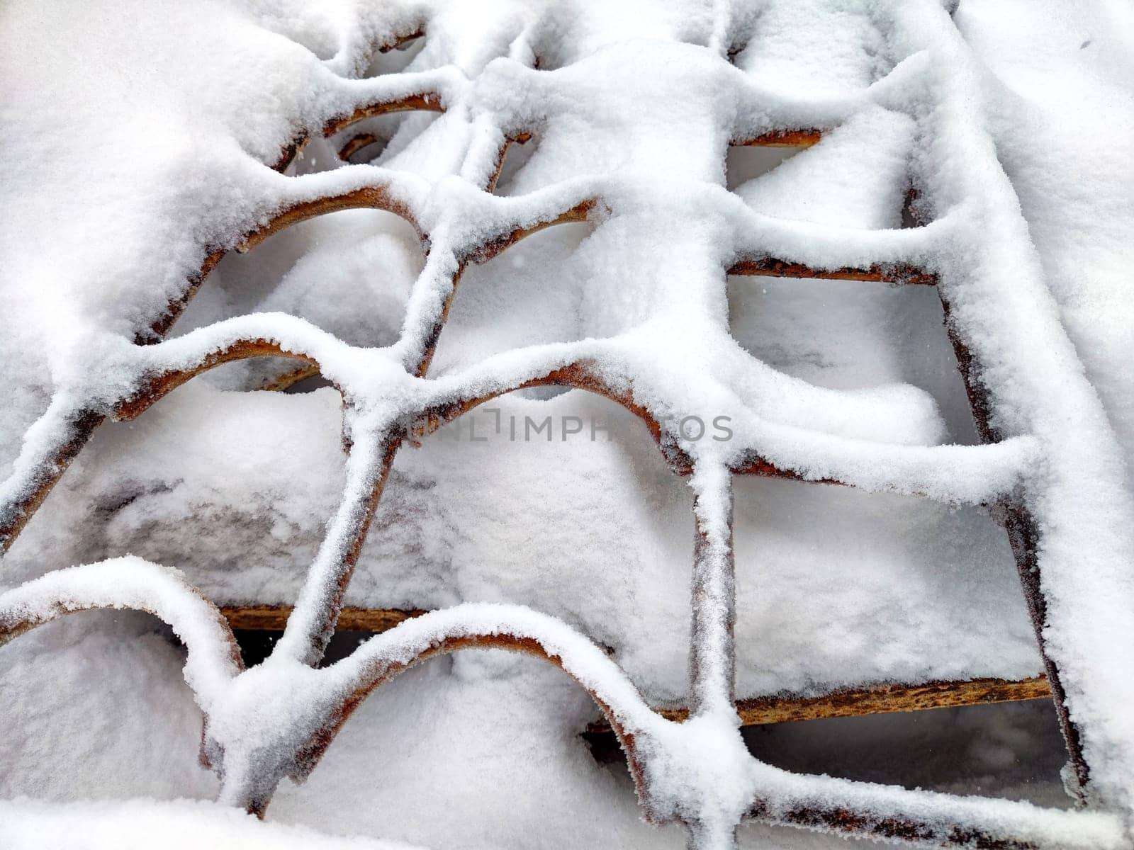 Wrought iron curly wavy lattice in the snow in winter. Abstract background, pattern, frame, texture, place for text, copy space