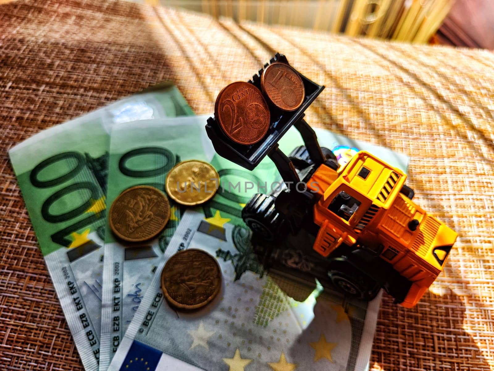 A small toy tractor or excavator on a bundle of money. The concept of the high cost of technology. The possibility of earning money with construction machinery by keleny