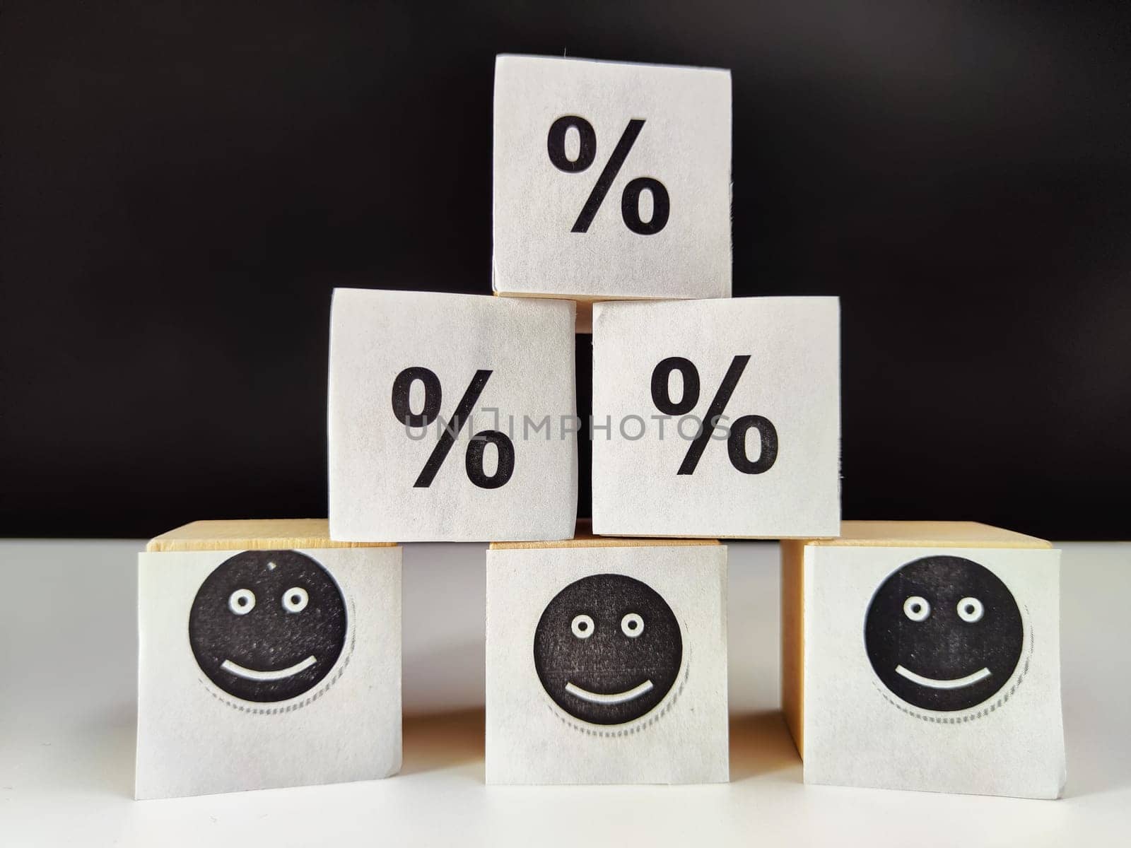 Wooden cubes in a column and row with white signs with a smiley sign, an arrow, a percentage. The concept of positivism. Positive thinking leads to the achievement of results and profits