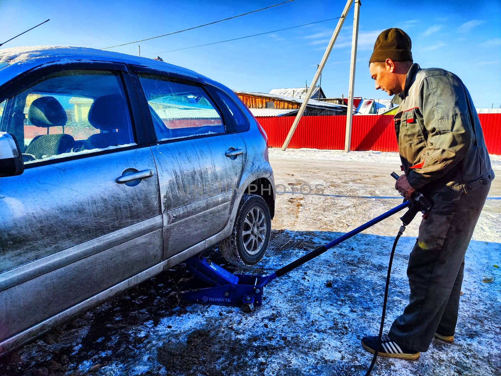 Ishim, Russia - November 27, 2023: A man makes tire of car wheel before cold snow season. Experienced mechanic changes wheel of car. The driver prepares a classic car for driving in the snow in winter by keleny