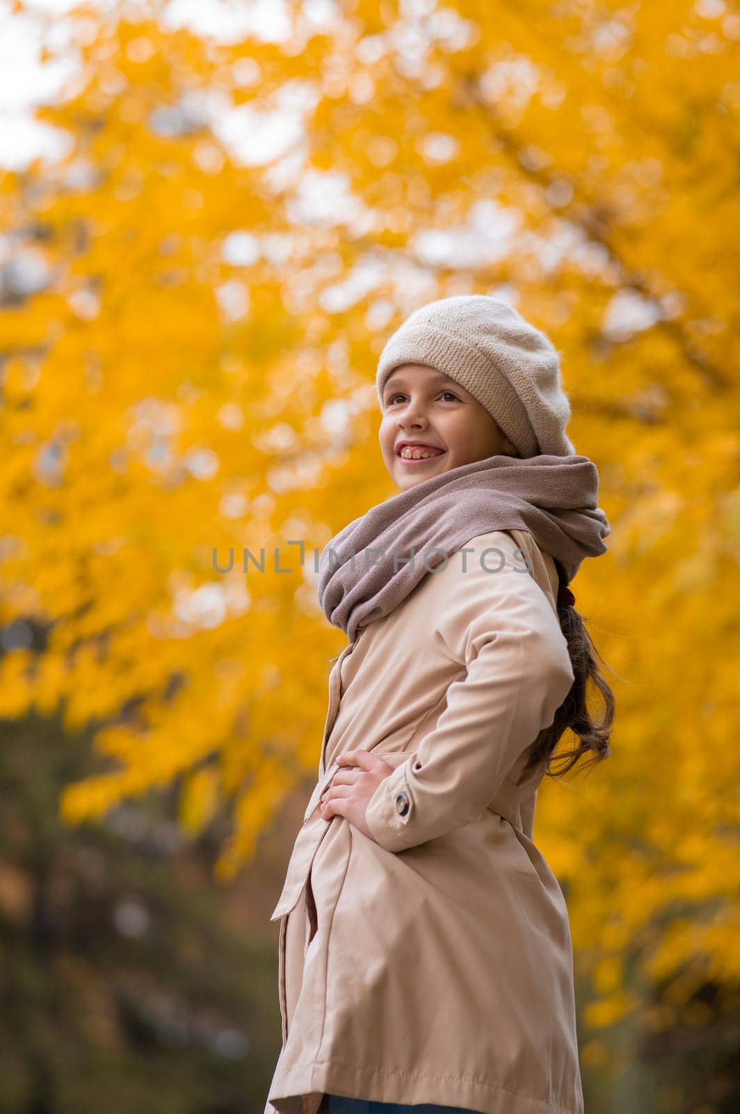 Happy caucasian girl in a beige coat and beret walks in the park in autumn. by mrwed54
