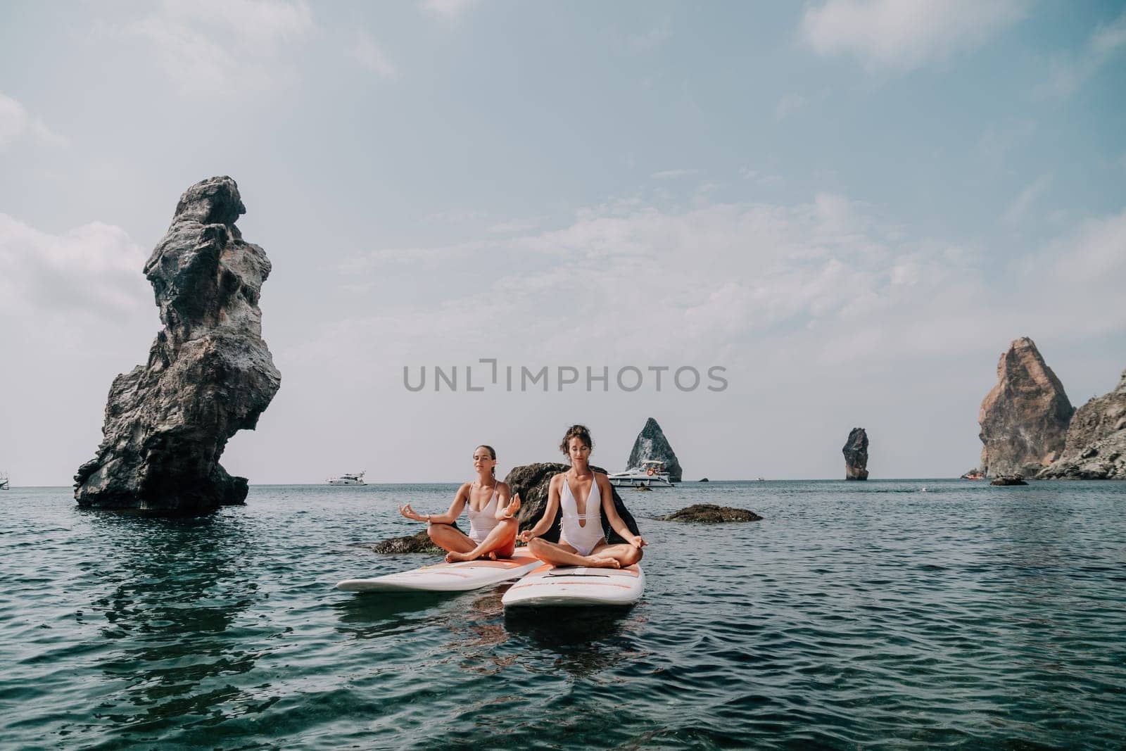 Woman sup yoga. Middle age sporty woman practising yoga pilates on paddle sup surfboard. Female stretching doing workout on sea water. Modern individual hipster outdoor summer sport activity