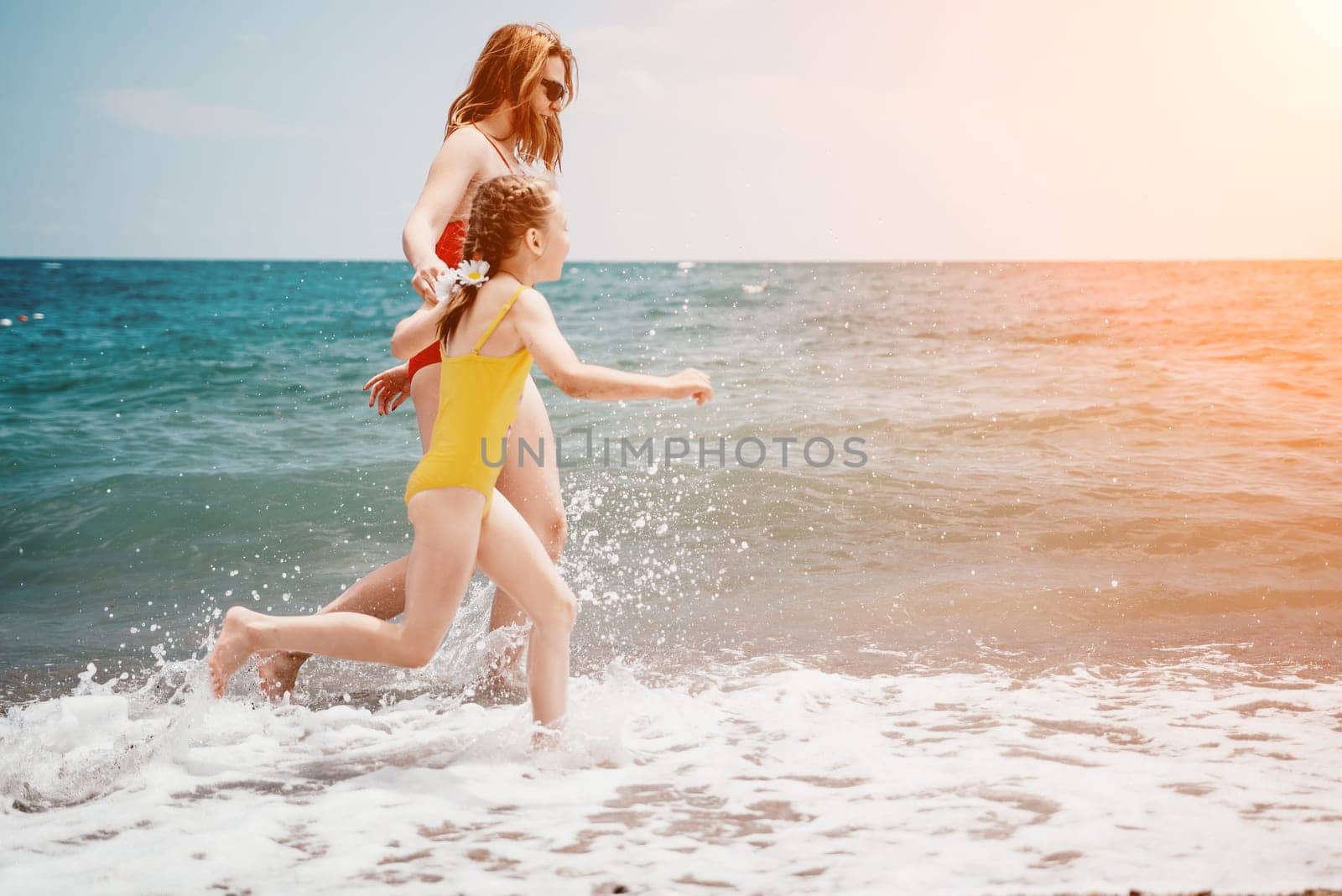 Happy loving family mother and daughter having fun together on the beach. Mum playing with her kid in holiday vacation next to the ocean - Family lifestyle and love concept by panophotograph