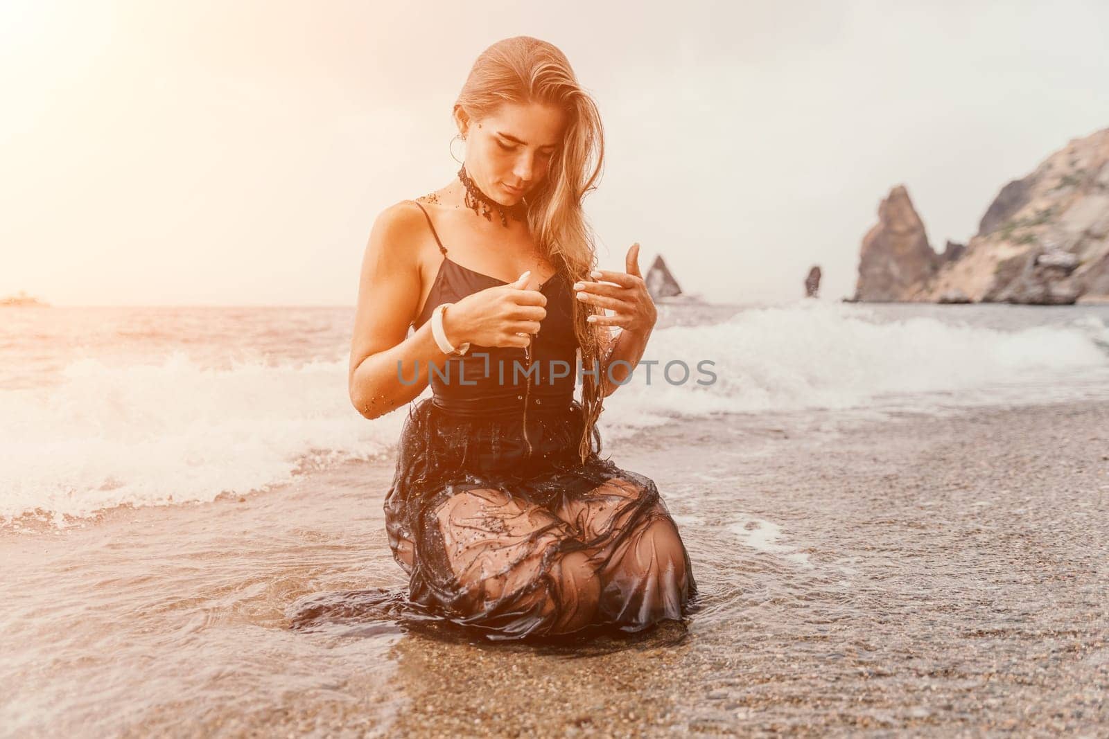 Woman summer travel sea. Happy tourist in black dress enjoy taking picture outdoors for memories. Woman traveler posing on sea beach surrounded by volcanic mountains, sharing travel adventure journey by panophotograph