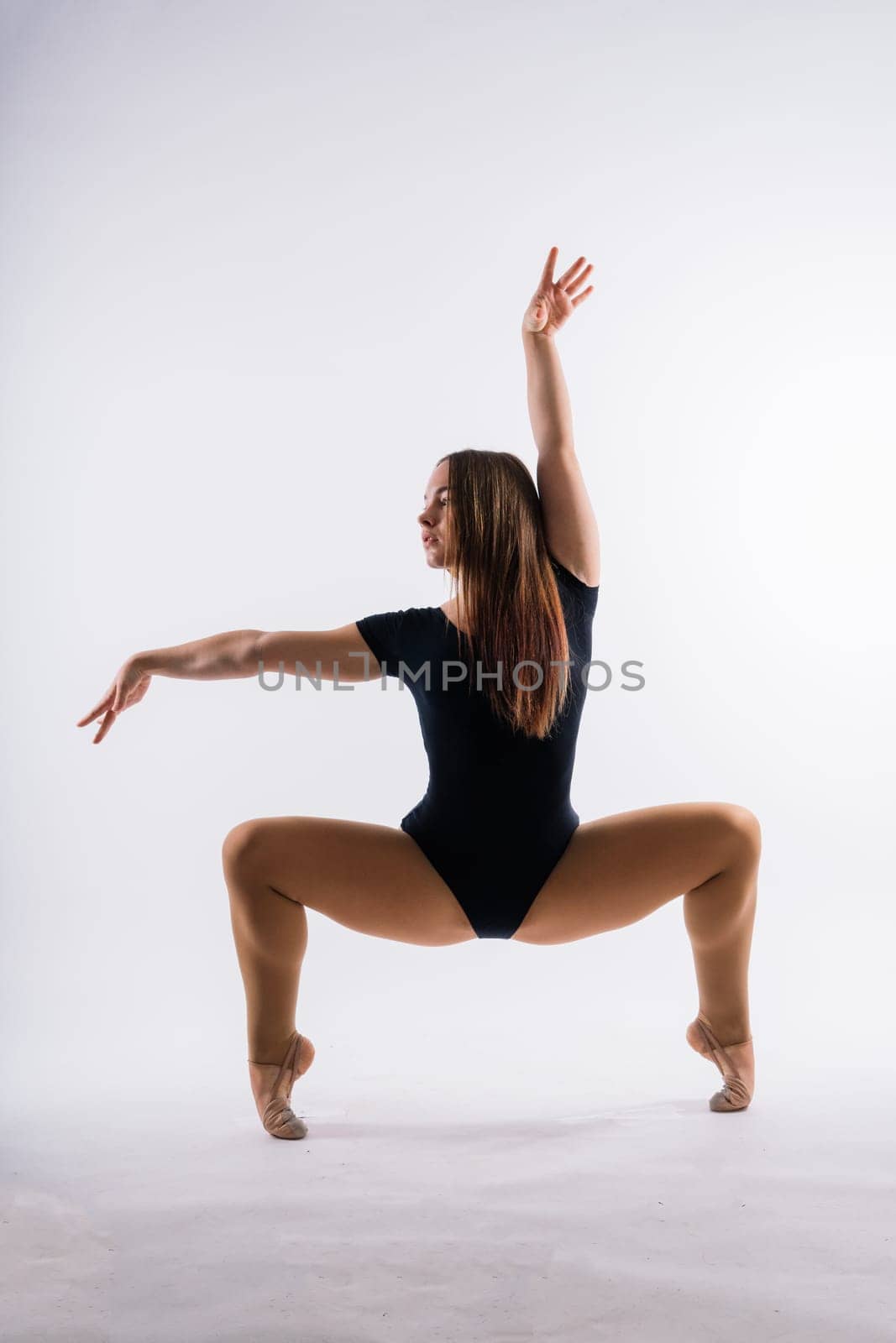 Beautiful plump brown-haired woman in black bodysuit in a studio. Caucasian dancehall dancer posing by Zelenin