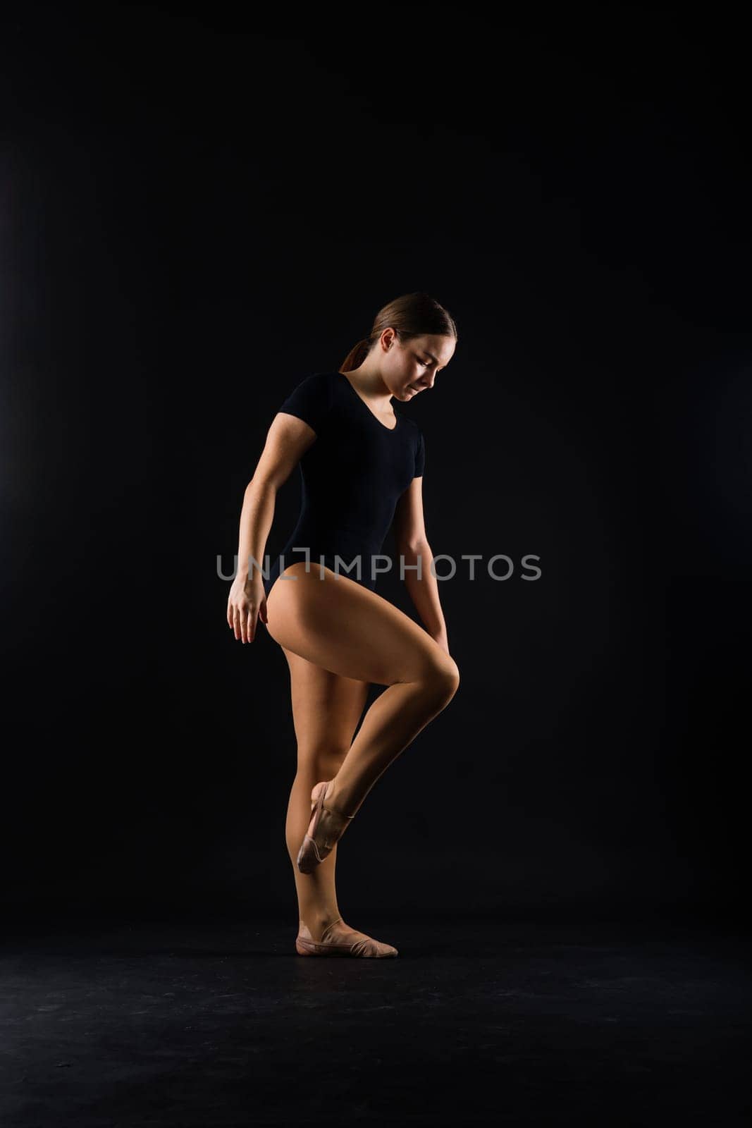 Beautiful plump brown-haired woman in black bodysuit in studio. Caucasian dancehall dancer posing