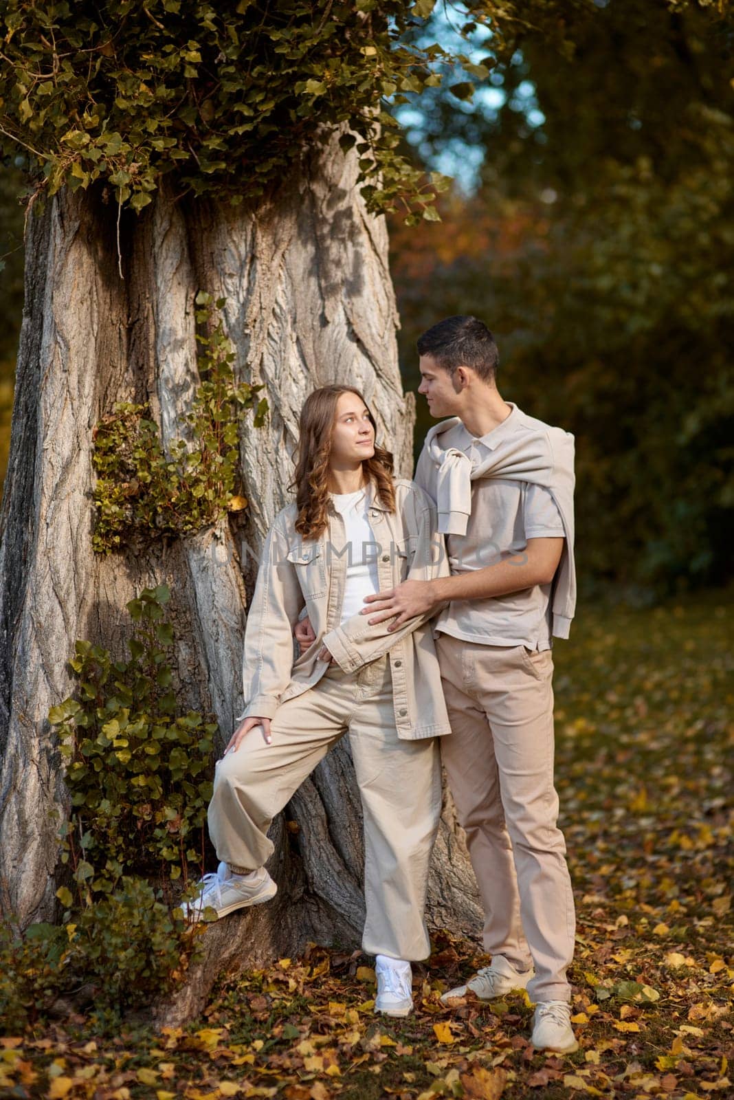 Young couple in love walking in the autumn park holding hands looking in the sunset. Closeup of loving couple holding hands while walking at sunset. The hands of the male and female lovers who hold hands walk forward high with blurred background