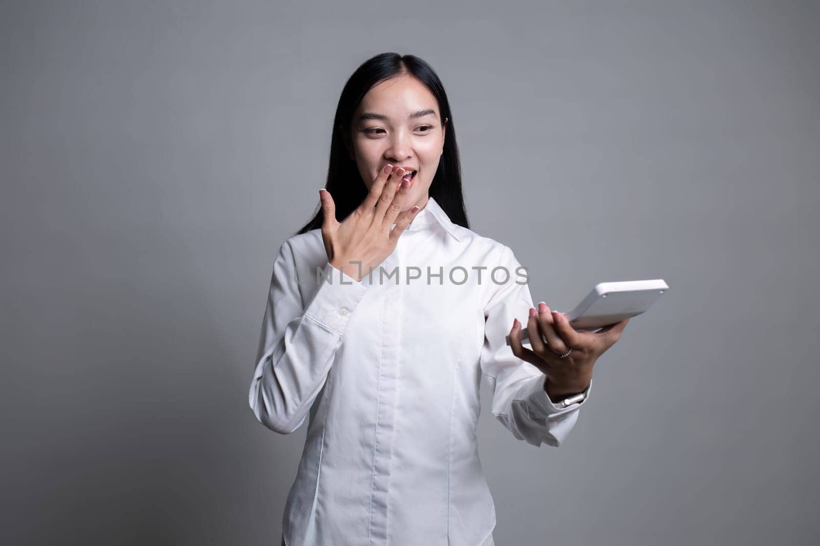 Portrait of a young accountant woman holding a calculator on a flat white background..