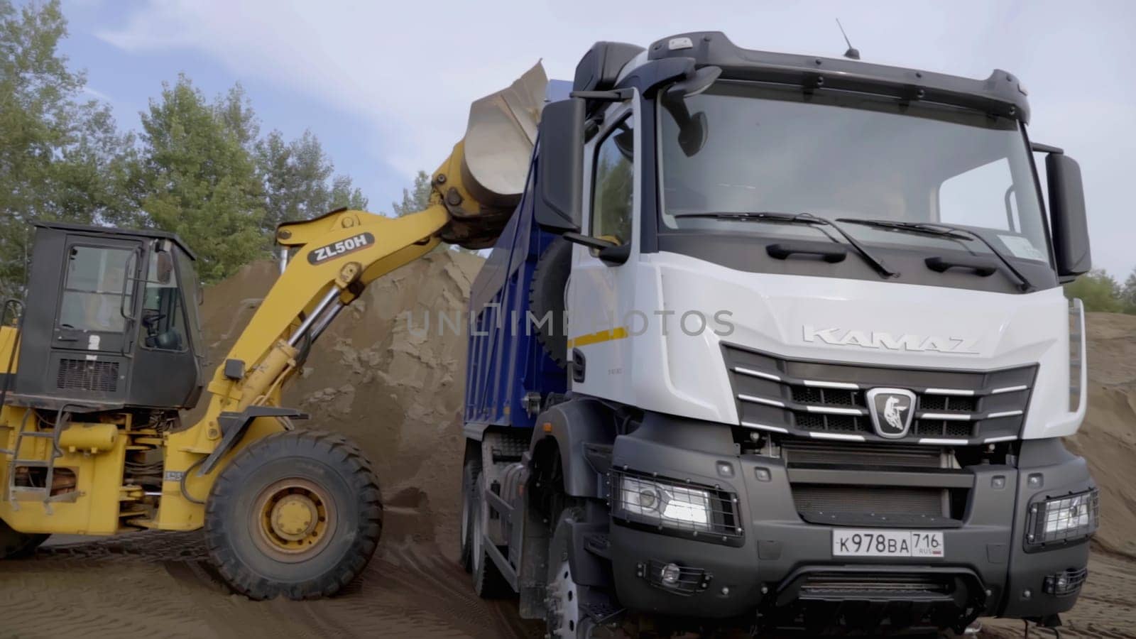 Berlin, Germany - June 20, 2022: industrial background with heavy machinery at work. Scene. Excavation work is being carried out on a construction site using an excavator for dumping earth loading into truck