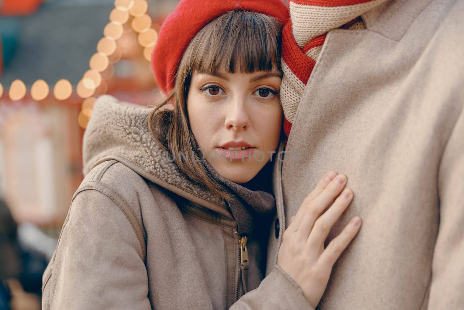 Young woman finding comfort in her partner's embrace at a festive outdoor Christmas market by Yaroslav_astakhov