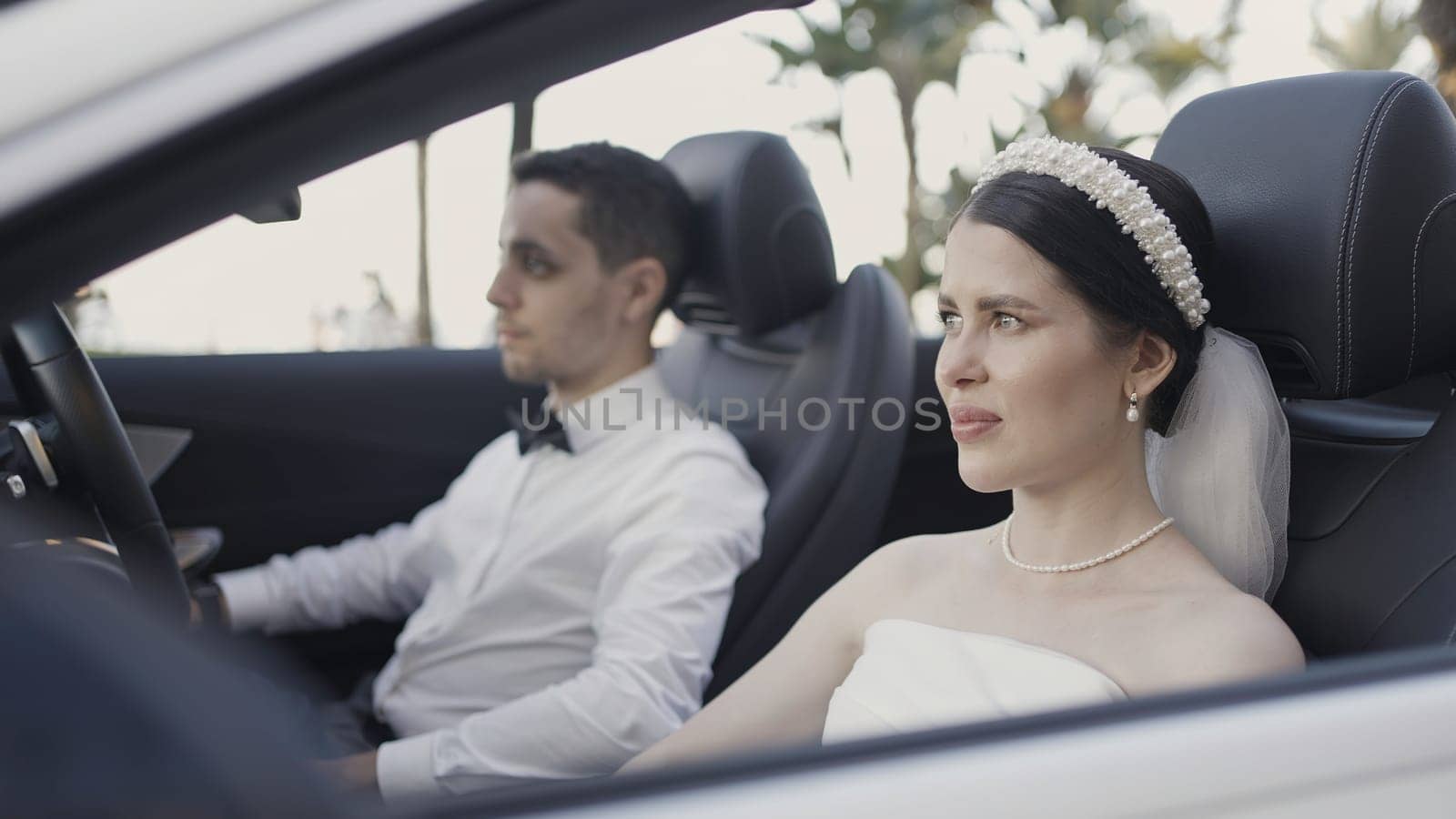 Beautiful couple in convertible. Action. Beautiful couple in festive elegant outfits in car. Couple in love in convertible on sunny summer day.